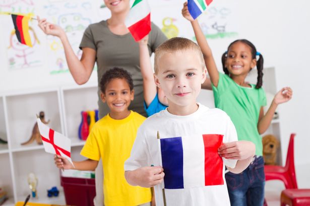 Enfants dans une salle de classe tenant des drapeaux nationaux pendant un cours de langues